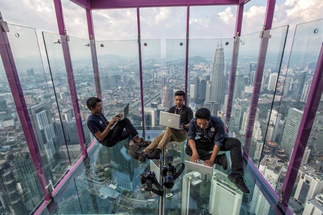 Varios periodistas trabajan en el mirador de cristal del rascacielos Kuala Lumpur Tower durante su presentación a los medios hoy, 5 de mayo de 2016 en Kuala Lumpur (Malasia). Esta atracción turística está situada a 421 metros de altura. EFE/Ahmad Yusni