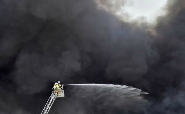 Bomberos en una escalera están sumidos en el humo, ya que sofocar un incendio en una instalación de almacenamiento de agua en el centro comercial de Dong Xuan en el distrito berlinés de Lichtenberg, el 11 de mayo de 2016. El humo afectó a varios barrios cercanos como el cuerpo de bomberos aconsejó a la gente a mantener su ventanas y puertas cerradas. John MACDOUGALL / AFP