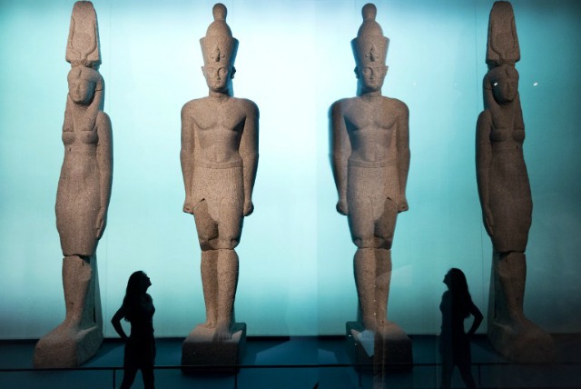 Un asistente de museo posa delante de estatuas del rey Ptolomeo II y Arsinoe de todo 283-246 antes de Cristo, en las ciudades sumergidas: mundos exposición perdida de Egipto en el Museo Británico de Londres el 17 de mayo de 2016. JUSTIN TALLIS / AFP