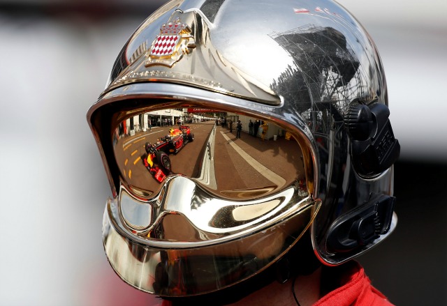 El coche de Red Bull Racing F1 de Max Verstappen se refleja en el casco de un bombero durante la primera práctica. REUTERS / Eric Gaillard