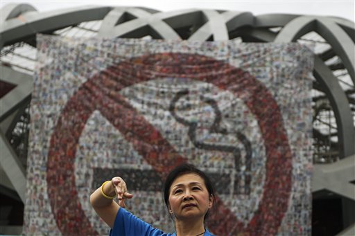 Una mujer actúa delante de una pancarta con el símbolo de prohibido fumar, colgada en el estadio olímpico Nido de Pájaro, durante la celebración del Dia Mundial Sin Tabaco, en Beijing, China, el 31 de mayo de 2016. (AP Foto/Andy Wong)