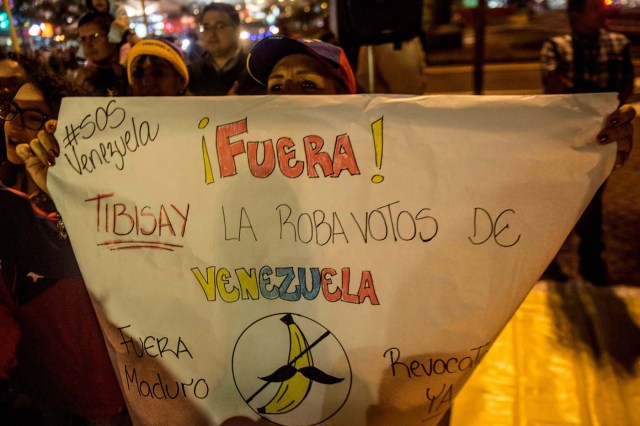 Venezuelan citizens in Peru hold signs during a protest against the visit of the president of the Venezuelan National Electoral Board (TSJ), Tibisay Lucena (not in frame), in Lima on June 01, 2016.  / AFP PHOTO / ERNESTO BENAVIDES