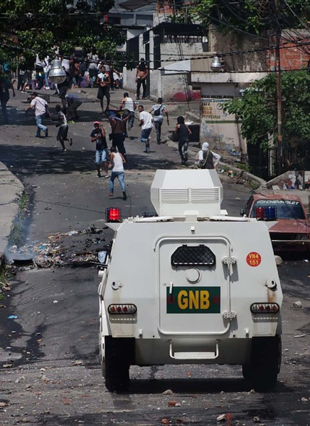 Riot police supported by National Guard armoured vehicles advance on demonstrators during clashes with residents of "La Vega" low income neighborhood, in Caracas on June 10, 2016. Facing mounting pressure from food shortages, looting and increasingly violent protests, Venezuelan authorities on Friday announced the next stage for a recall referendum against embattled President Nicolas Maduro. / AFP PHOTO / STR