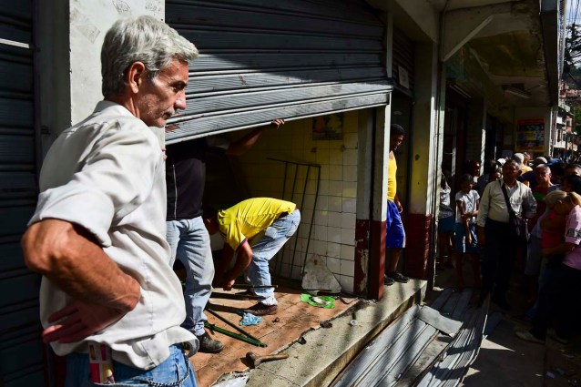 A butcher and residents of the poor neighbourhood of Petare in Caracas repair the butcher's shop looted during the early morning on June 10, 2016. Venezuela President Nicolas Maduro faces mounting protests over shortages of food, medicine, electricity and water. / AFP PHOTO / RONALDO SCHEMIDT