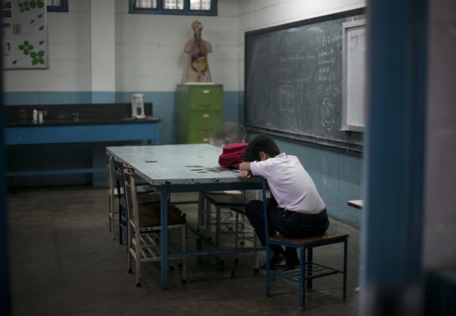 Fotografía del 1 de junio de 2016 muestra a un estudiante apoyando la cabeza sobre un escritorio durante una clase en una escuela secundaria pública en Caracas, Venezuela. La tasa anual de abandono de escuela secundaria se duplicó a 11% desde 2011 y a las escuelas les falta personal debido a que profesionales están abandonando el país. (AP Foto/Ariana Cubillos)