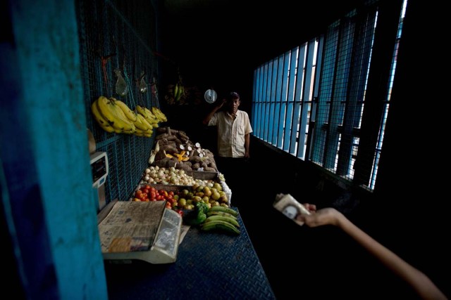 En esta imagen, tomada el 31 de mayo de 2016, un joven sostiene un billete de 100 bolívares (alrededor de un 1 dólar) para comprar yuca en un mercado de la barriada de Petare, en Caracas, Venezuela. Productos como el mango, la batata, el ñame, la yuca, el plátano o las sardinas, que antes no eran muy demandados por los venezolanos, ahora en medio de la crisis se han convertido para muchos en su principal o único alimento. Algunos recurren a la agricultura urbana para hacer que las verduras frescas sigan siendo parte de sus dietas, ya que comprarlas en el mercado es un lujo. (AP Foto/Fernando Llano)