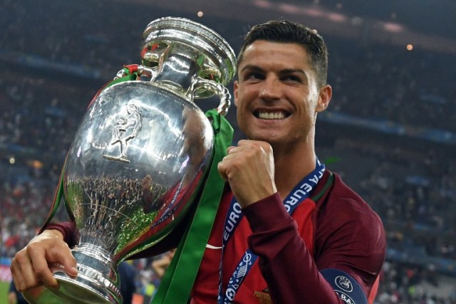 Portugal's forward Cristiano Ronaldo smiles while posing with the trophy after Portugal won the Euro 2016 final football match between Portugal and France at the Stade de France in Saint-Denis, north of Paris, on July 10, 2016. / AFP PHOTO / FRANCISCO LEONG