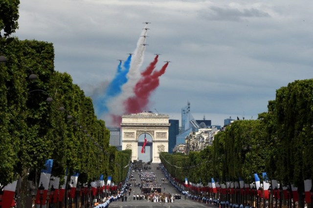 Alphajet aircrafts from the French elite acrobatic flying team Patrouille de France (PAF) release smoke in the colours of the French national flag during the annual Bastille Day military parade on the Champs-Elysees avenue in Paris on July 14, 2016. France holds annual Bastille Day military parade with troops from Australia and New Zealand as special guests among the 3,000 soldiers who will march up the Champs Elysees avenue. They will be accompanied by 200 vehicles with 85 aircraft flying overhead. / AFP PHOTO / DOMINIQUE FAGET