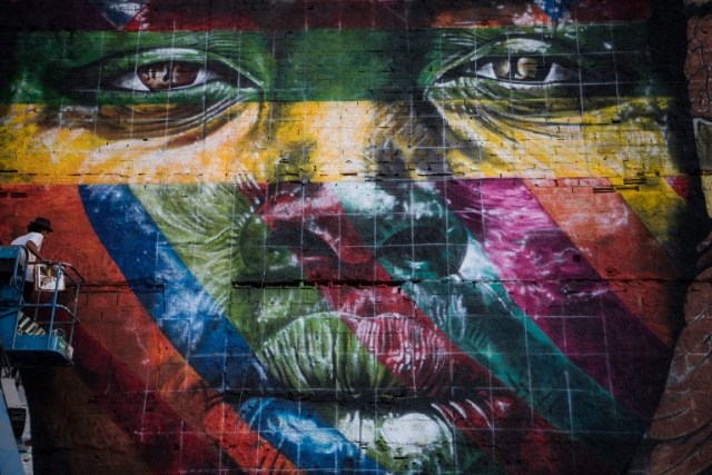 Assistants to Brazilian artist Eduardo Kobra work on the painting of a huge mural representing the five continents, at the Olympic Boulevard, in Rio de Janeiro, Brazil, on July 14, 2016. / AFP PHOTO / CHRISTOPHE SIMON