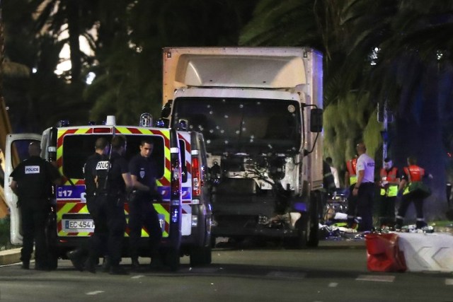 Police officers and rescue workers stand near a van that ploughed into a crowd leaving a fireworks display in the French Riviera town of Nice on July 14, 2016. The mayor of the French city of Nice said dozens of people were likely killed after a van rammed into a crowd marking Bastille Day in the French Riviera resort today and urged residents to stay indoors. / AFP PHOTO / VALERY HACHE