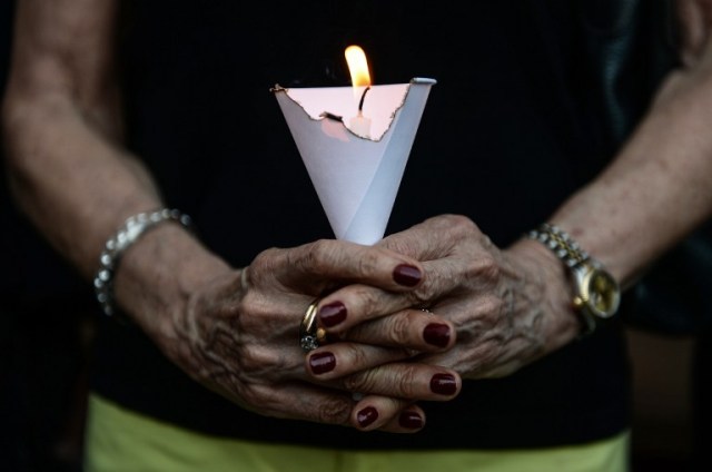 A member of the French community holds a candle during a vigil in Bangkok on July 15, 2016. A gunman smashed a truck into a crowd of revellers celebrating Bastille Day on July 14, 2016 in the French Riviera city of Nice, killing at least 84 people in what President Francois Hollande called a "terrorist" attack. / AFP PHOTO / LILLIAN SUWANRUMPHA
