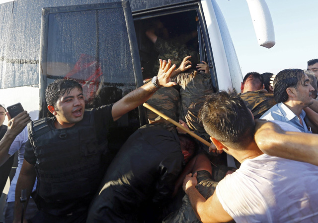 A policeman protects soldiers from the mob after troops involved in the coup surrendered on the Bosphorus Bridge in Istanbul, Turkey July 16, 2016. REUTERS/Murad Sezer