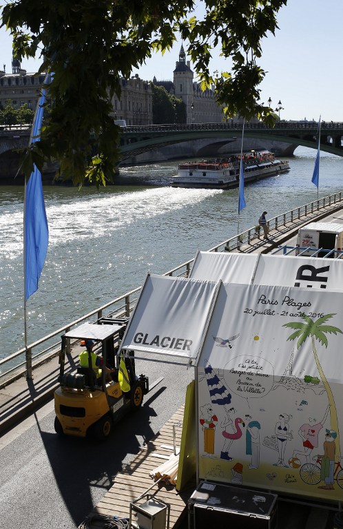 A man drives a vehicle past an ice cream booth, on July 19, 2016 in Paris, along the banks of the river Seine, during preparations on the eve of the opening of Paris Plages. The 15th edition of Paris Plages will run from July 20 until September 4, 2016. / AFP PHOTO / MATTHIEU ALEXANDRE