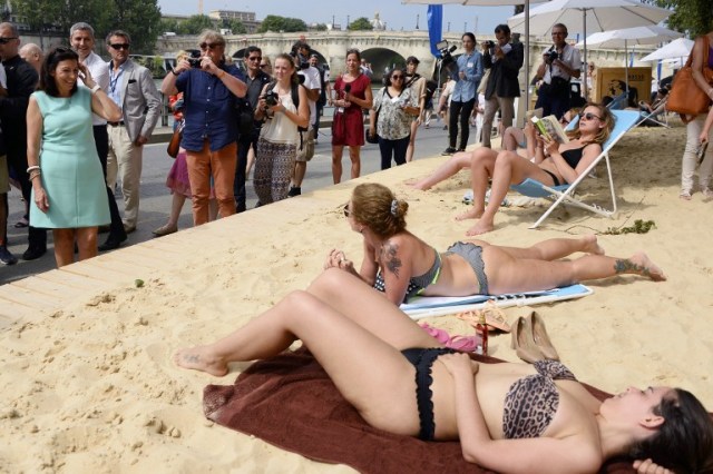 Mayor of Paris Anne Hidalgo (L) talks to sunbathing women as she visits "Paris Plage" (Paris Beach) during the opening day of the event on the bank of the Seine river, in central Paris, on July 20, 2016. The 15th edition of Paris Plage will run until September 4, 2016. / AFP PHOTO / BERTRAND GUAY