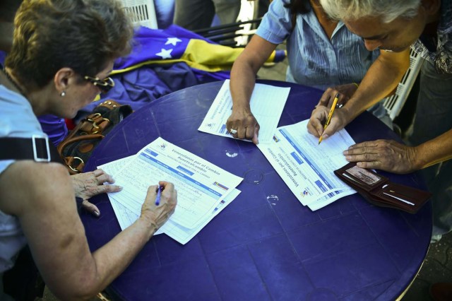(FILES) This file photo taken on June 06, 2016 shows people signing a form during an opposition demonstration for a recall vote in Caracas. Venezuelans civil servants reported on July 18, 2016, that signing a referendum on removing President Nicolas Maduro left them without their job. 1,250 civil servants were dismissed for backing the referendum according to UNETE labour union, which will report the cases to the International Labour Organization (ILO). / AFP PHOTO / RONALDO SCHEMIDT