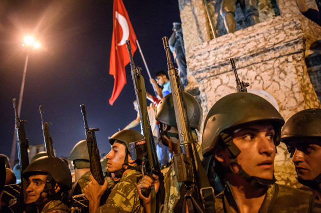 EDITORS NOTE: Graphic content / Turkish solders stay at Taksim square as people protest against the military coup in Istanbul on July 16, 2016. Turkish military forces on July 16 opened fire on crowds gathered in Istanbul following a coup attempt, causing casualties, an AFP photographer said. The soldiers opened fire on grounds around the first bridge across the Bosphorus dividing Europe and Asia, said the photographer, who saw wounded people being taken to ambulances. / AFP PHOTO / OZAN KOSE