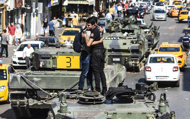 EDITORS NOTE: Graphic content / Turkish police officer (R) embrace a man on a tank after the military position was taken over at the Anatolian side at Uskudar in Istanbul on July 16, 2016. President Recep Tayyip Erdogan urged Turks to remain on the streets on July 16, 2016, as his forces regained control after a spectacular coup bid by discontented soldiers that claimed more than 250 lives. Describing the attempted coup as a "black stain" on Turkey's democracy, Yildirim said that 161 people had been killed in the night of violence and 1,440 wounded. / AFP PHOTO / BULENT KILIC