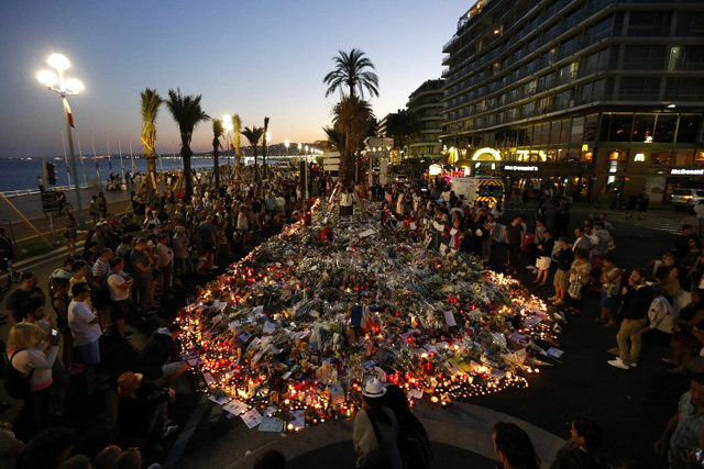 People gather at a makeshift memorial on the Promenade des Anglais in Nice on July 17, 2016, in tribute to the victims of the Bastille Day attack that left 84 dead. The Islamic State group claimed responsibility for the truck attack that killed 84 people in Nice on France's national holiday, a news service affiliated with the jihadists said on July 16. Tunisian Mohamed Lahouaiej-Bouhlel, 31, smashed a 19-tonne truck into a packed crowd of people in the Riviera city celebrating Bastille Day -- France's national day. / AFP PHOTO / Valery HACHE