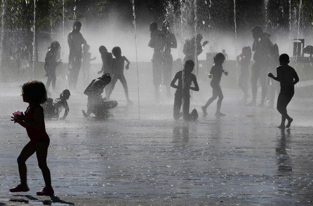 Youngsters play with the water of fountains on the banks of the Manzanares river in Madrid on July 18, 2016. / AFP PHOTO / JAVIER SORIANO