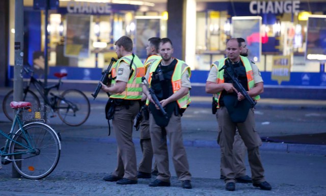 Police officers stand guard outside the main train station following a shooting rampage at the Olympia shopping mall in Munich, Germany July 22, 2016. REUTERS/Michael Dalder