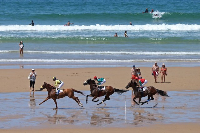 Jockeys and their mounts race along the beach during the annual beach horse race in Loredo, near the northern Spanish city of Santander, on July 24, 2016. / AFP PHOTO / CESAR MANSO