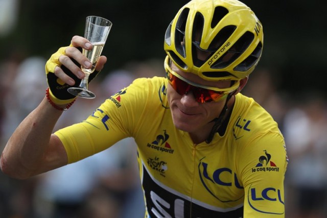 Great Britain's Christopher Froome, wearing the overall leader's yellow jersey, is handed a glass of champagne as he rides during the 113 km twenty-first and last stage of the 103rd edition of the Tour de France cycling race on July 24, 2016 between Chantilly and Paris Champs-Elysees. / AFP PHOTO / KENZO TRIBOUILLARD