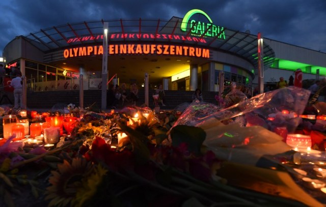 Candles and flowers lie in front of the Olympia Einkaufszentrum shopping centre on July 24, 2016 in Munich, southern Germany, where an 18-year-old German-Iranian student run amok. Europe reacted in shock to the third attack on the continent in just over a week, after David Ali Sonboly went on a shooting spree at a shopping centre on July 22, 2016 in what appears to have been a premeditated attack, before turning the gun on himself. / AFP PHOTO / CHRISTOF STACHE