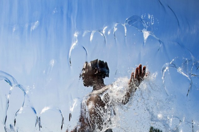 A boy walks through a waterfall on July 25, 2016 while playing in the water at The Yards Park in Washington, DC, as a heat wave rolls across the area. / AFP PHOTO / JIM WATSON