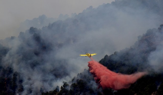 A plane fights a wildfire burning in Artana, near Castellon, eastern Spain, on July 26, 2016. A wildfire, still active on more than 1,000 hectares in the region of Valencia (eastern Spain), hit a natural park and made the army to intervene, said today regional authorities. / AFP PHOTO / JOSE JORDAN