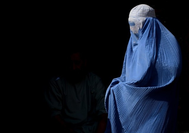 A burqa-clad Afghan woman walks along a road in Herat on July 28, 2016. / AFP PHOTO / AREF KARIMI
