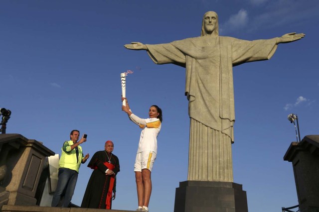 REFILE - ADDITIONAL INFORMATION2016 Rio Olympics - Olympic torch - Rio de Janeiro, Brazil 05/08/2016. Former Brazilian volleyball player Isabel Barroso holds the Olympic torch next to Christ the Redeemer statue watched by Rio Mayor Eduardo Paes (L) and archbishop Orani Joao Tempesta. REUTERS/Pilar Olivares