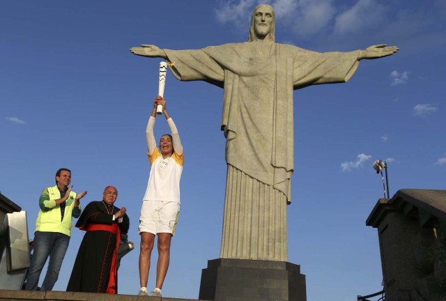 REFILE - ADDITIONAL INFORMATION2016 Rio Olympics - Olympic torch - Rio de Janeiro, Brazil 05/08/2016. Former Brazilian volleyball player Isabel Barroso holds the Olympic torch next to Christ the Redeemer statue as Rio Mayor Eduardo Paes (L) and archbishop Orani Joao Tempesta applaud. REUTERS/Pilar Olivares