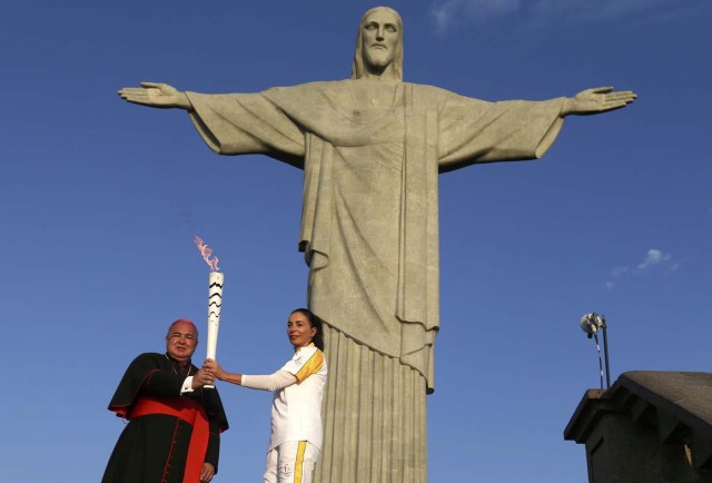 Rio Olympics - Olympic torch - Rio de Janeiro, Brazil 05/08/2016. Former Brazilian volleyball player Isabel Barroso and archbishop Orani Joao Tempesta (L) hold the Olympic torch next to Christ the Redeemer statue. REUTERS/Pilar Olivares