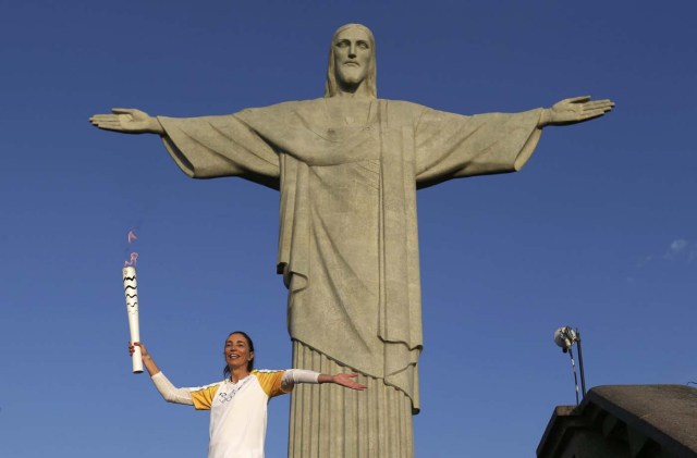 Rio Olympics - Olympic torch - Rio de Janeiro, Brazil 05/08/2016. Former Brazilian volleyball player Isabel Barroso holds the Olympic torch next to Christ the Redeemer statue. REUTERS/Pilar Olivares TPX IMAGES OF THE DAY