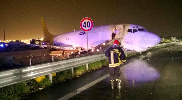 A firefighter stands in front of a cargo plane that exited the runway after landing and slid onto a local road in Orio al Serio, next to Milan, Italy, in this August 5, 2016 handout picture provided by Italy's Fire Fighters. Vigili del Fuoco/Handout via REUTERS ATTENTION EDITORS - THIS IMAGE WAS PROVIDED BY A THIRD PARTY. EDITORIAL USE ONLY. TPX IMAGES OF THE DAY