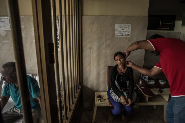 Un médico pincha la oreja de Soraya Rodríguez durante una prueba de sangre para detectar la malaria en una clínica de Tumeremo. Credit Meridith Kohut para The New York Times