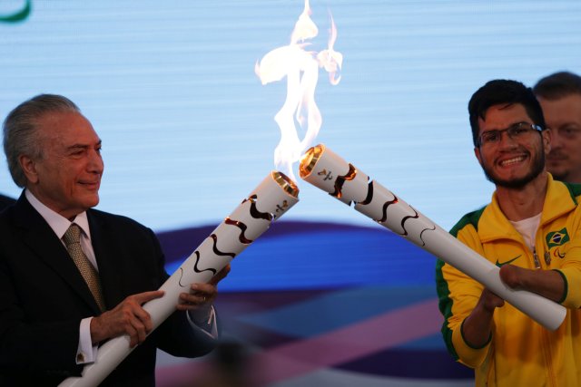 Brazil's interim President Michel Temer lights the torch with the Paralympic flame from Paralympian Yohansson do Nascimento during the Paralympics Flame torch relay launching ceremony at Planalto Palace in Brasilia, Brazil, August 25, 2016. REUTERS/Ueslei Marcelino