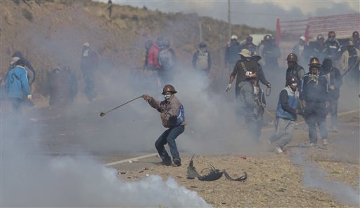 En esta imagen del jueves 25 de agosto de 2016, mineros independientes chocan con la policía mientras huyen de gases lacrimógenos durante unas protestas en Panduro, Bolivia. Miles de mineros independientes continauron con sus protestas, con cortes de carreteras, que precipitaron los enfrentamientos cuando la policía intentó desalojarlos. Durante los choques, varios mineros secuestraron y mataron a golpes al viceministro de Régimen Interior, en un chocante brote de violencia tras semanas de tensiones. (AP Foto/Juan Karita)