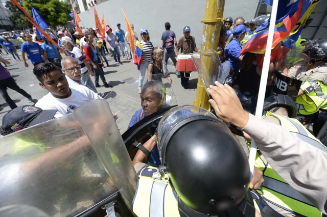 Venezuelan opposition activists argue with police during a march in Caracas on September 16, 2016 demanding to the government to set the date for a recall referendum against President Nicolas Maduro. The Venezuelan opposition's push for a vote to remove President Maduro ran into a roadblock Thursday when authorities announced a delay in setting the date for the final stage in the process. / AFP PHOTO / FEDERICO PARRA