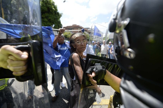 Venezuelan opposition activists argue with police during a march in Caracas on September 16, 2016 demanding to the government to set the date for a recall referendum against President Nicolas Maduro. The Venezuelan opposition's push for a vote to remove President Maduro ran into a roadblock Thursday when authorities announced a delay in setting the date for the final stage in the process. / AFP PHOTO / FEDERICO PARRA
