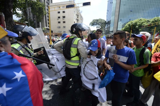 Venezuelan opposition activists are blocked by police during a march in Caracas on September 16, 2016 demanding to the government to set the date for a recall referendum against President Nicolas Maduro. The Venezuelan opposition's push for a vote to remove President Maduro ran into a roadblock Thursday when authorities announced a delay in setting the date for the final stage in the process. / AFP PHOTO / FEDERICO PARRA