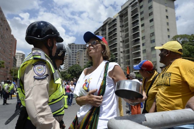 Venezuelan opposition activists are blocked by police during a march in Caracas on September 16, 2016 demanding to the government to set the date for a recall referendum against President Nicolas Maduro. The Venezuelan opposition's push for a vote to remove President Maduro ran into a roadblock Thursday when authorities announced a delay in setting the date for the final stage in the process. / AFP PHOTO / FEDERICO PARRA