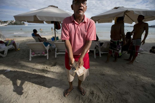 En esta imagen, tomada el 14 de septiembre de 2016, Nicolás Millán, que gestiona un restaurante en la playa, muestra dinero en efectivo mientras se lamenta de lo poco que ganó ese día: 1.000 bolívares (alrededor de un dólar), en la playa de Pampatar, en la isla de Margarita, Venezuela. Hace una década, el 40% de los turistas que visitaban la isla de Margarita eran extranjeros, según el presidente de la Cámara de Turismo, Igor Viloria. Ahora solo el 4% de los turistas son foráneos. (AP Foto/Ariana Cubillos)