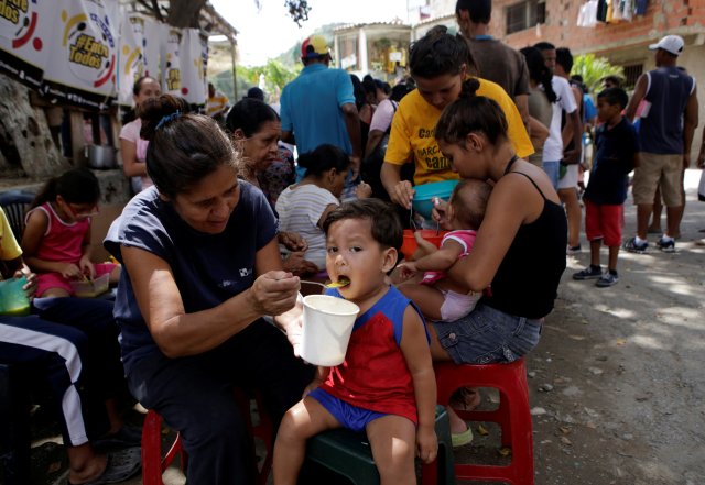People eat free food which was prepared by residents and volunteers on a street in the low-income neighborhood of Caucaguita in Caracas, Venezuela September 17, 2016. REUTERS/Henry Romero