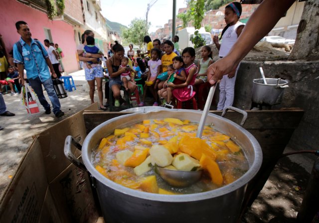 A volunteer prepares food to be distributed for free among residents on a street in the low-income neighborhood of Caucaguita near Caracas, Venezuela September 17, 2016. REUTERS/Henry Romero