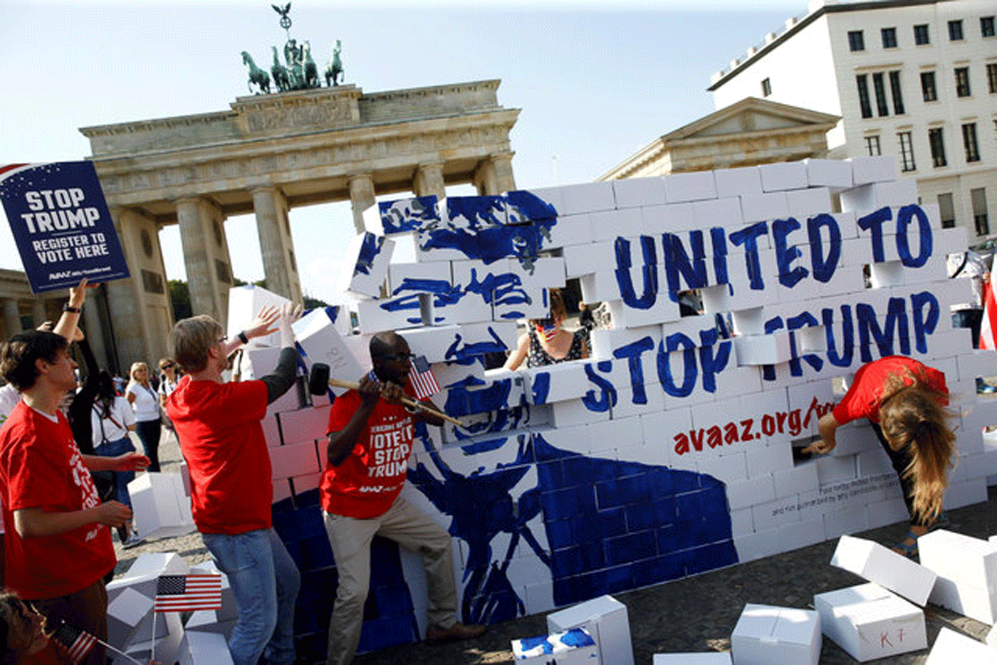 Activistas levantan y derriban un muro de Trump ante la Puerta de Brandeburgo, en Berlín