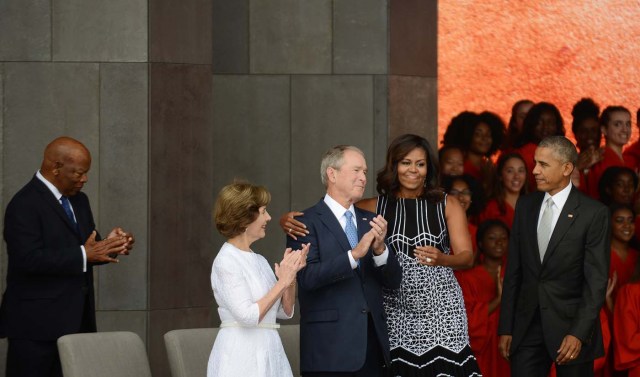 WASHINGTON, DC - SEPTEMBER 24: President Barack Obama watches first lady Michelle Obama embracing former president George Bush, accompanied by his wife, former first lady Laura Bush, while participating in the dedication of the National Museum of African American History and Culture September 24, 2016 in Washington, DC, before the museum opens to the public later that day. The museum is a Smithsonian Institution museum located on the National Mall featuring African American history and culture in the US. Astrid Riecken/Getty Images/AFP