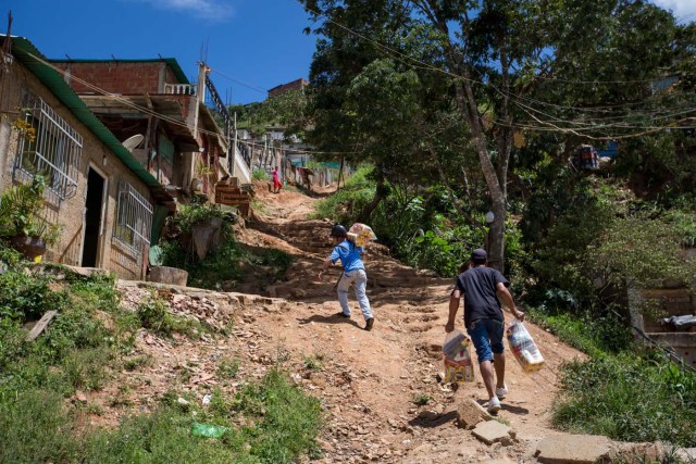 ACOMPAÑA CRÓNICA: VENEZUELA ALIMENTOS - CAR01. CARACAS (VENEZUELA), 28/08/2016.- Fotografía del 20 de agosto del 2016, donde se observa a un grupo de personas cargando bolsas de comida durante un operativo de entrega de bolsas de comida a habitantes de un barrio del km 3 del Junquito por parte Comités Locales de Abastecimiento y Producción (CLAP) en Caracas (Venezuela). La severa escasez de productos básicos en Venezuela ha llevado a que la foto diaria del país sea una inmensa fila frente a muchos abastos y supermercados, un problema que el Gobierno intenta solucionar con un sistema de venta de alimentos, conformado solo por militantes chavistas, conocido como CLAP. EFE/MIGUEL GUTIÉRREZ