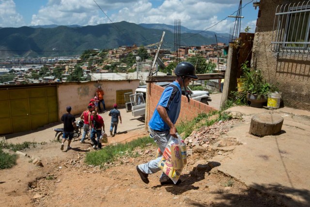 ACOMPAÑA CRÓNICA: VENEZUELA ALIMENTOS - CAR01. CARACAS (VENEZUELA), 28/08/2016.- Fotografía del 20 de agosto del 2016, donde se observa a un grupo de personas cargando bolsas de comida durante un operativo de entrega de bolsas de comida a habitantes de un barrio del km 3 del Junquito por parte Comités Locales de Abastecimiento y Producción (CLAP) en Caracas (Venezuela). La severa escasez de productos básicos en Venezuela ha llevado a que la foto diaria del país sea una inmensa fila frente a muchos abastos y supermercados, un problema que el Gobierno intenta solucionar con un sistema de venta de alimentos, conformado solo por militantes chavistas, conocido como CLAP. EFE/MIGUEL GUTIÉRREZ