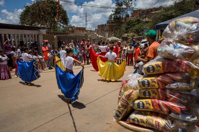 ACOMPAÑA CRÓNICA: VENEZUELA ALIMENTOS - CAR01. CARACAS (VENEZUELA), 28/08/2016.- Fotografía del 20 de agosto del 2016, donde se observa un grupo de bailarinas durante un operativo de entrega de bolsas de comida a habitantes de un barrio del km 3 del Junquito por parte Comités Locales de Abastecimiento y Producción (CLAP) en Caracas (Venezuela). La severa escasez de productos básicos en Venezuela ha llevado a que la foto diaria del país sea una inmensa fila frente a muchos abastos y supermercados, un problema que el Gobierno intenta solucionar con un sistema de venta de alimentos, conformado solo por militantes chavistas, conocido como CLAP. EFE/MIGUEL GUTIÉRREZ